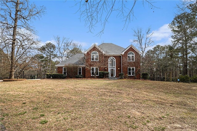 traditional-style home with brick siding and a front lawn