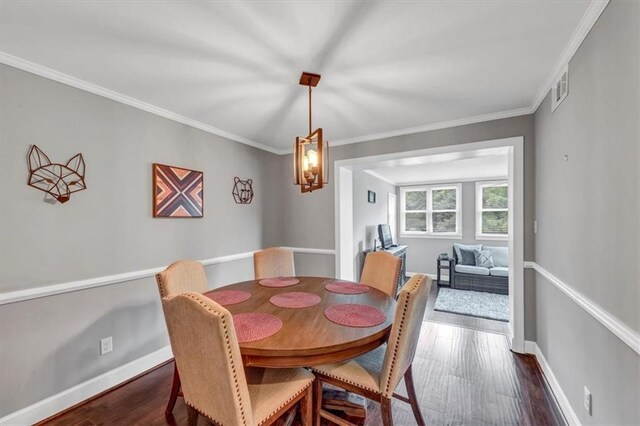 dining space with ornamental molding and dark hardwood / wood-style floors