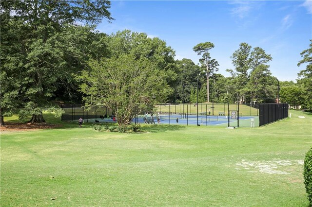 view of community featuring a lawn and tennis court