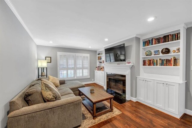 living room featuring crown molding, wood-type flooring, and built in shelves