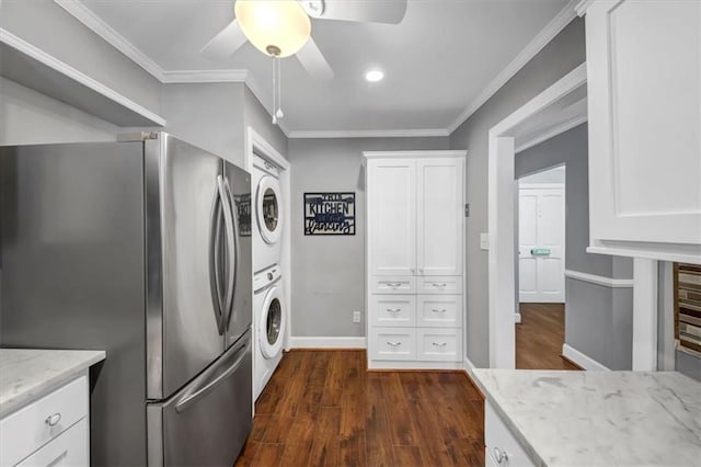 kitchen with dark hardwood / wood-style flooring, ornamental molding, white cabinets, stacked washer / drying machine, and stainless steel refrigerator