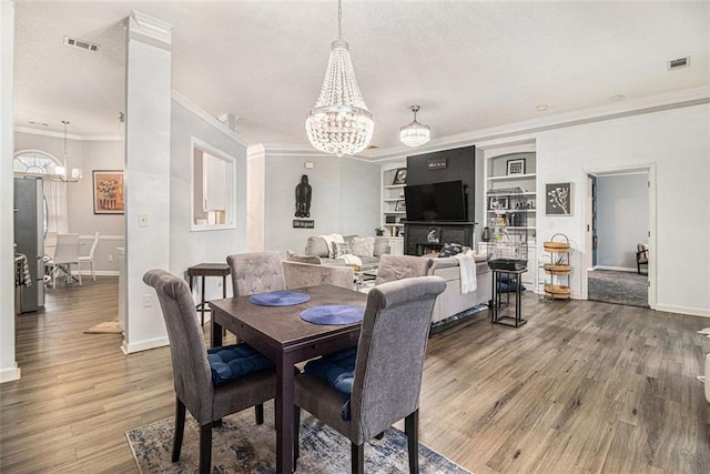 dining area featuring a notable chandelier, built in shelves, and wood-type flooring