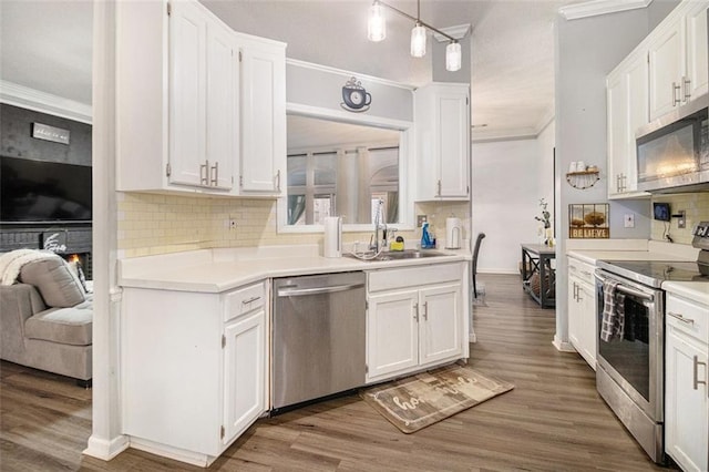 kitchen featuring appliances with stainless steel finishes, decorative backsplash, ornamental molding, sink, and white cabinetry