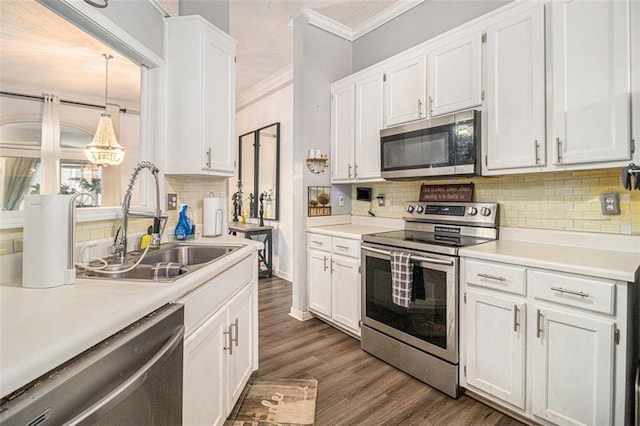 kitchen featuring decorative light fixtures, sink, stainless steel appliances, and white cabinetry