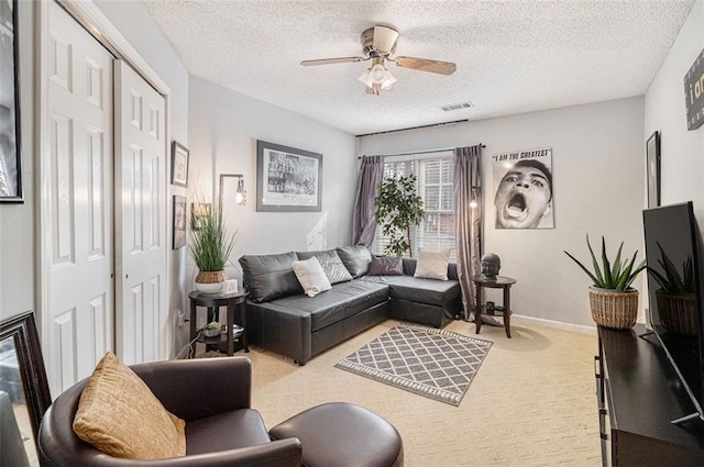 carpeted living room featuring ceiling fan and a textured ceiling