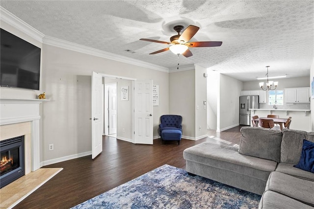 living room featuring a textured ceiling, crown molding, dark wood-type flooring, and ceiling fan with notable chandelier