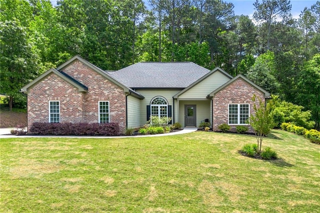 view of front of home featuring brick siding, a front lawn, and view of scattered trees