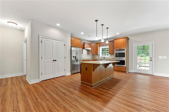 kitchen with stainless steel appliances, light wood-type flooring, a breakfast bar area, brown cabinets, and recessed lighting