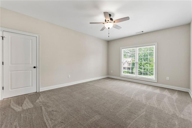 carpeted spare room with a ceiling fan and baseboards