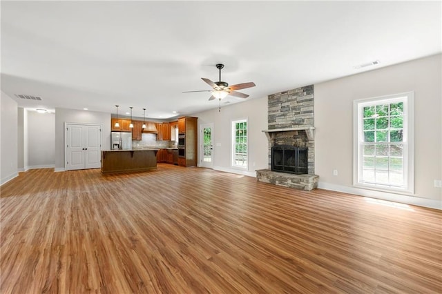 unfurnished living room with light wood-type flooring, ceiling fan, baseboards, a fireplace, and recessed lighting