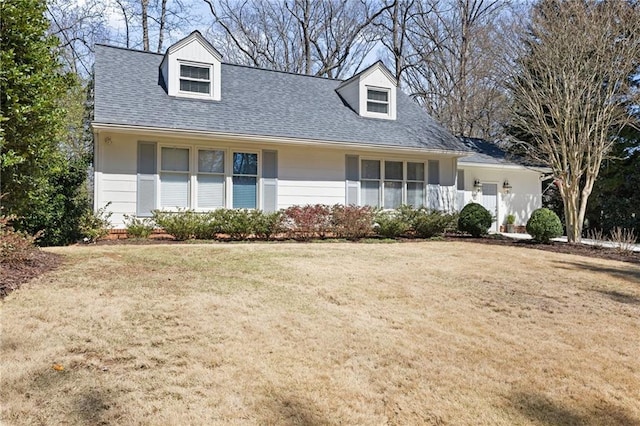 cape cod home with a front yard and a shingled roof