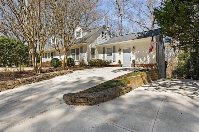 cape cod home featuring brick siding and driveway