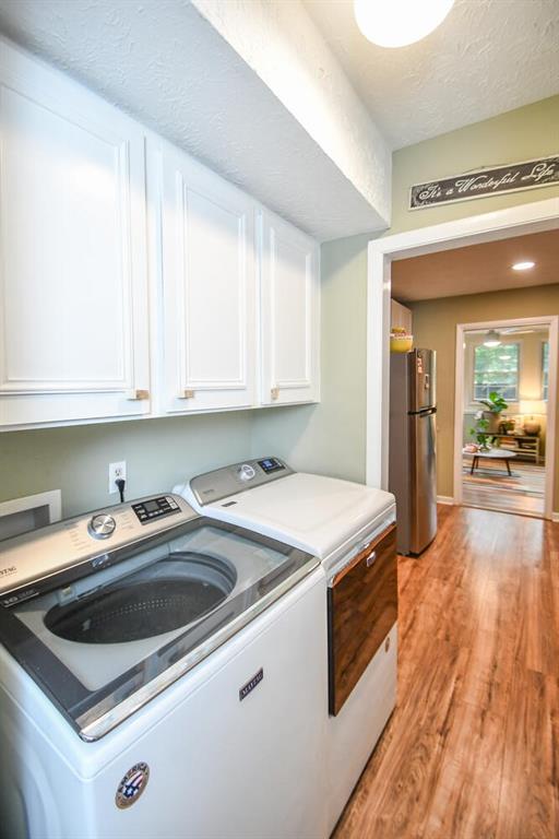 1235 Riverside Dr Unit H3, Gainesville, GA 30501 - laundry area featuring a textured ceiling, light wood finished floors, washing machine and dryer, and cabinet space