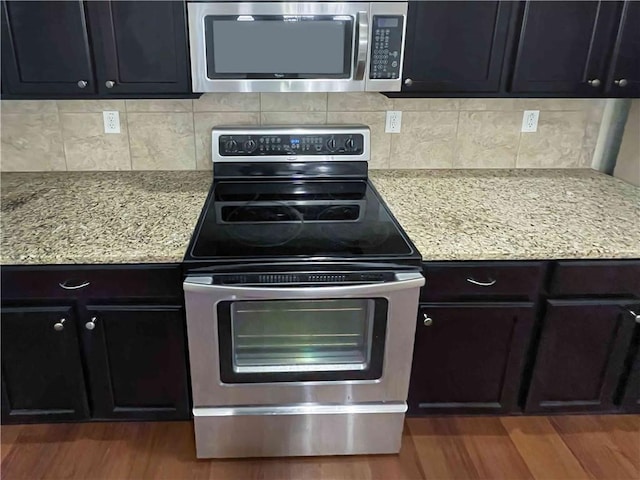 kitchen featuring light stone countertops, backsplash, appliances with stainless steel finishes, and wood finished floors