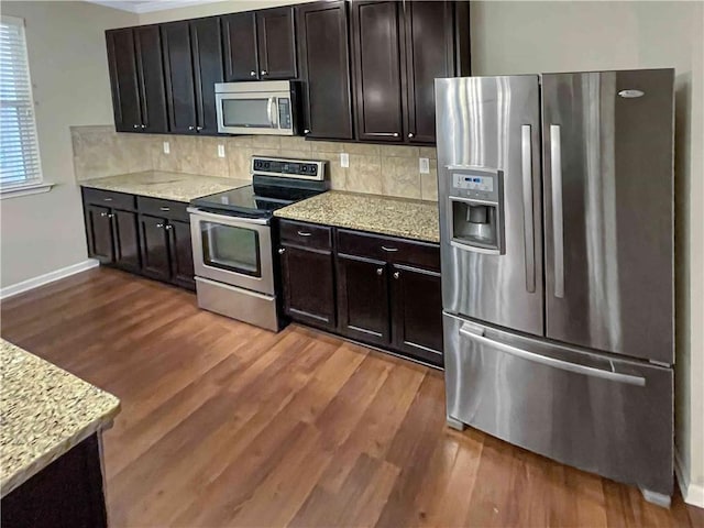 kitchen featuring decorative backsplash, stainless steel appliances, dark wood-type flooring, and light stone countertops