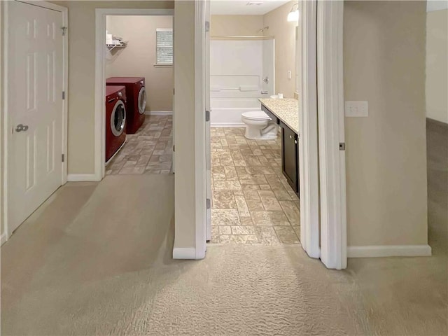 hallway with stone finish flooring, baseboards, and washing machine and clothes dryer