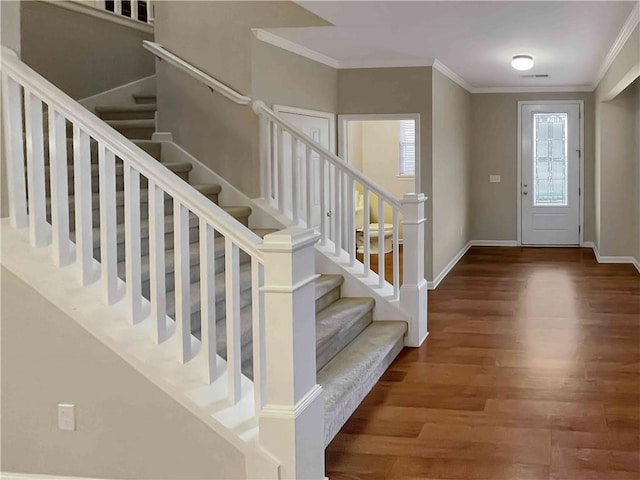 foyer with stairway, wood finished floors, baseboards, and ornamental molding