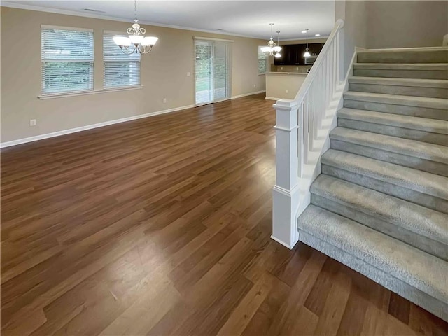 staircase featuring an inviting chandelier, wood finished floors, baseboards, and ornamental molding