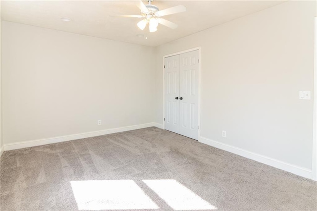 spare room featuring light carpet, ceiling fan, and baseboards