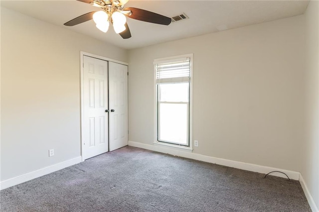 unfurnished bedroom featuring baseboards, visible vents, a ceiling fan, carpet floors, and a closet