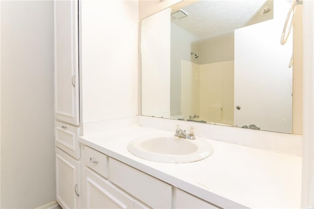 bathroom with visible vents, walk in shower, and vanity