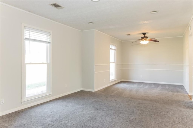 carpeted empty room with baseboards, visible vents, and crown molding