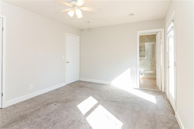 unfurnished bedroom featuring light carpet, ensuite bathroom, a ceiling fan, and baseboards