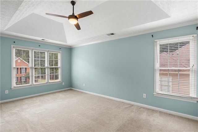 carpeted empty room featuring a textured ceiling, crown molding, a tray ceiling, and ceiling fan