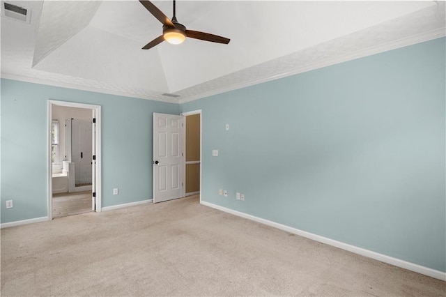 unfurnished bedroom featuring ceiling fan, a raised ceiling, crown molding, light colored carpet, and ensuite bath