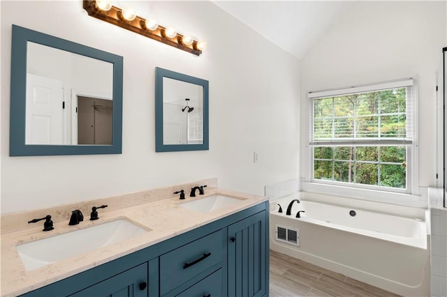 bathroom with vanity, hardwood / wood-style flooring, a tub to relax in, and vaulted ceiling