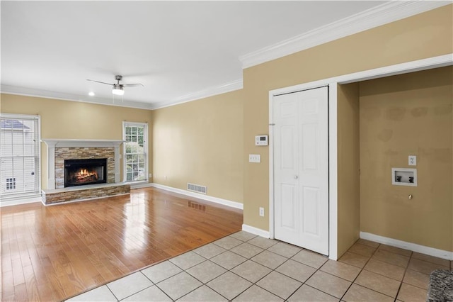 unfurnished living room featuring light hardwood / wood-style flooring, ornamental molding, ceiling fan, and a fireplace