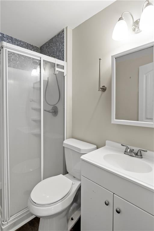 bathroom with vanity, toilet, and a shower with shower door