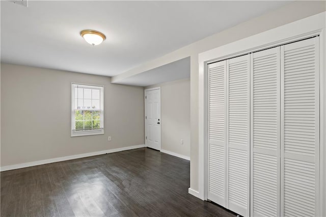 unfurnished bedroom featuring a closet and dark hardwood / wood-style flooring