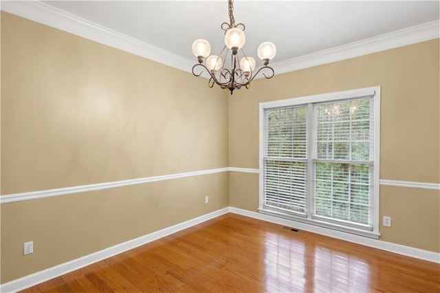 spare room with a chandelier, hardwood / wood-style flooring, and crown molding