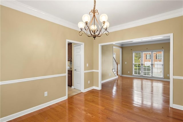 unfurnished room with crown molding, light hardwood / wood-style flooring, and a notable chandelier