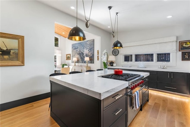 kitchen featuring light wood-type flooring, a kitchen island, hanging light fixtures, and high end stainless steel range oven