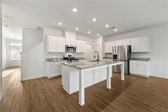 kitchen with visible vents, an island with sink, appliances with stainless steel finishes, dark wood-type flooring, and a sink