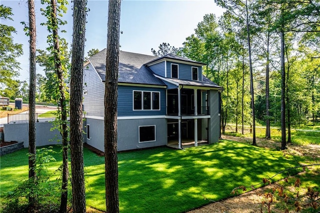 rear view of property with a sunroom, a yard, and a shingled roof