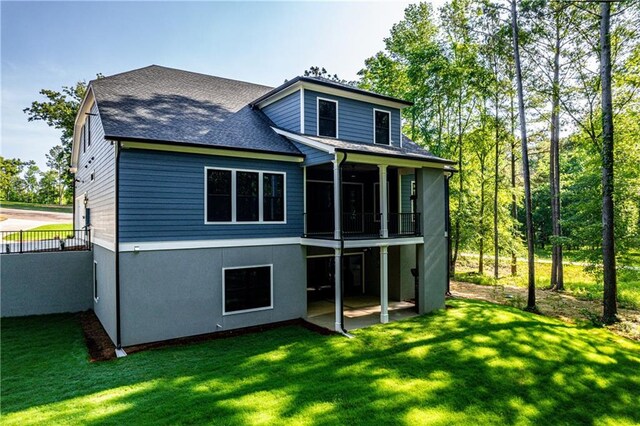 back of house featuring a yard, roof with shingles, and a patio area