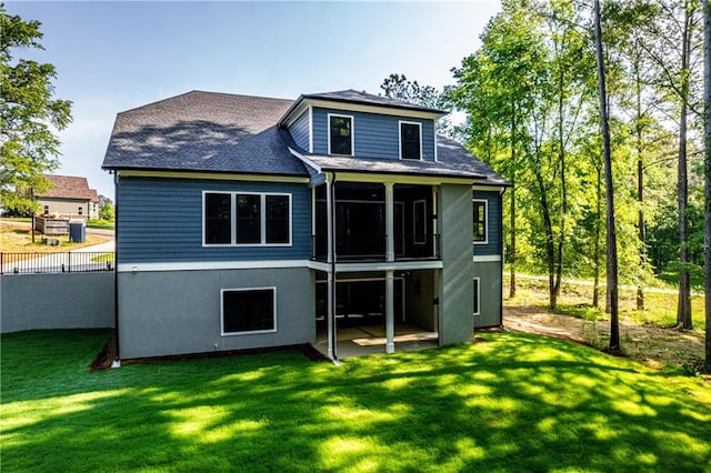 back of house featuring a yard, a shingled roof, a sunroom, stucco siding, and a patio
