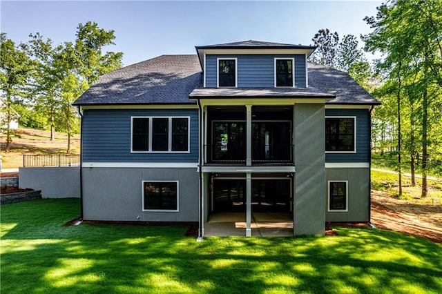 rear view of property featuring a patio, a yard, and roof with shingles