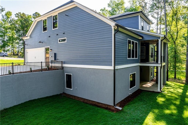 view of side of home featuring a lawn, a garage, a balcony, and driveway