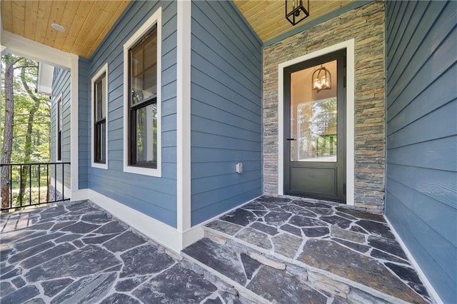 doorway to property featuring covered porch and stone siding