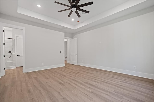 empty room with a raised ceiling, a ceiling fan, light wood-style flooring, baseboards, and recessed lighting