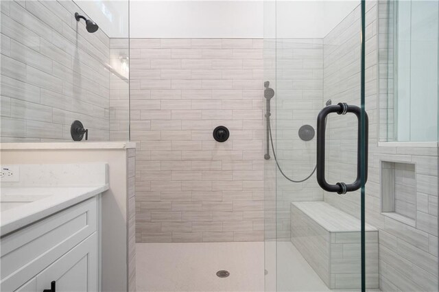 bathroom with a tile shower and vanity
