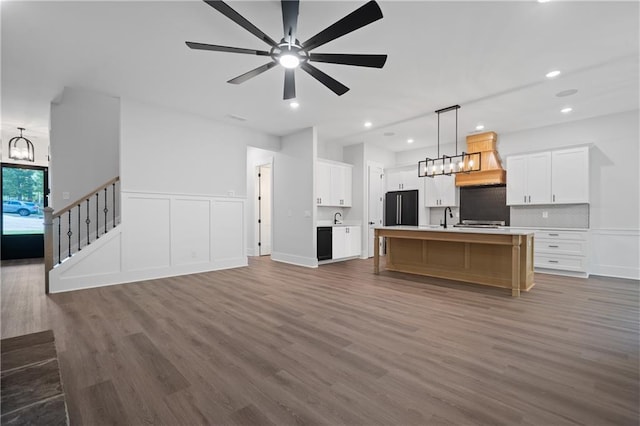 unfurnished living room with a sink, wood finished floors, ceiling fan, a chandelier, and recessed lighting