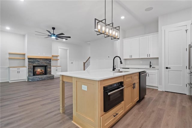 kitchen featuring a sink, dishwasher, oven, light countertops, and ceiling fan