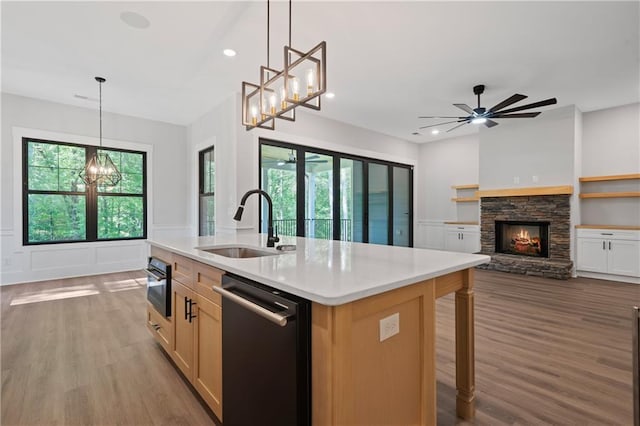 kitchen with dishwashing machine, a sink, a chandelier, wood finished floors, and light countertops