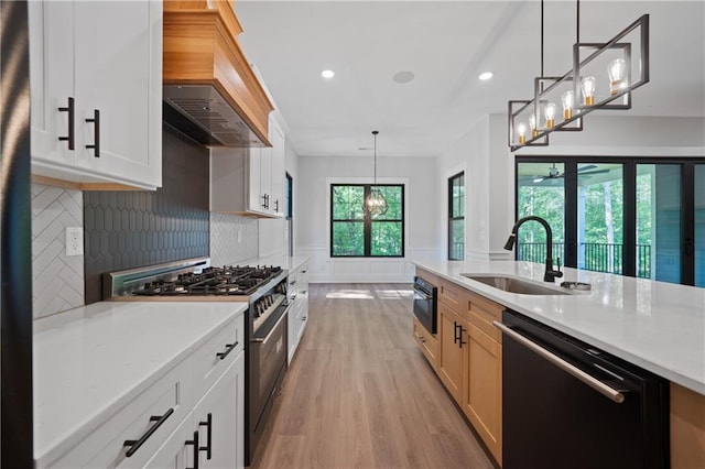 kitchen with black appliances, a sink, premium range hood, light wood-style floors, and a chandelier