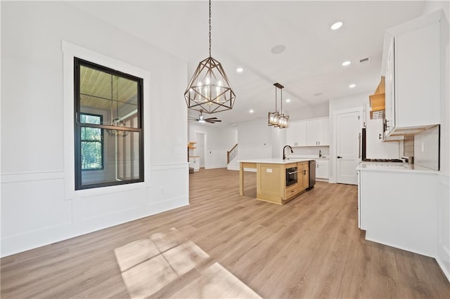 kitchen featuring light wood finished floors, a sink, light countertops, a kitchen island with sink, and recessed lighting